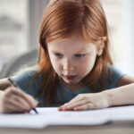 A young student concentrating while writing at a desk